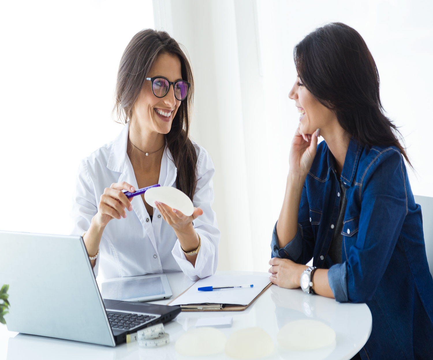 Portrait of doctor and her patient choosing mammary prosthesis in the office.